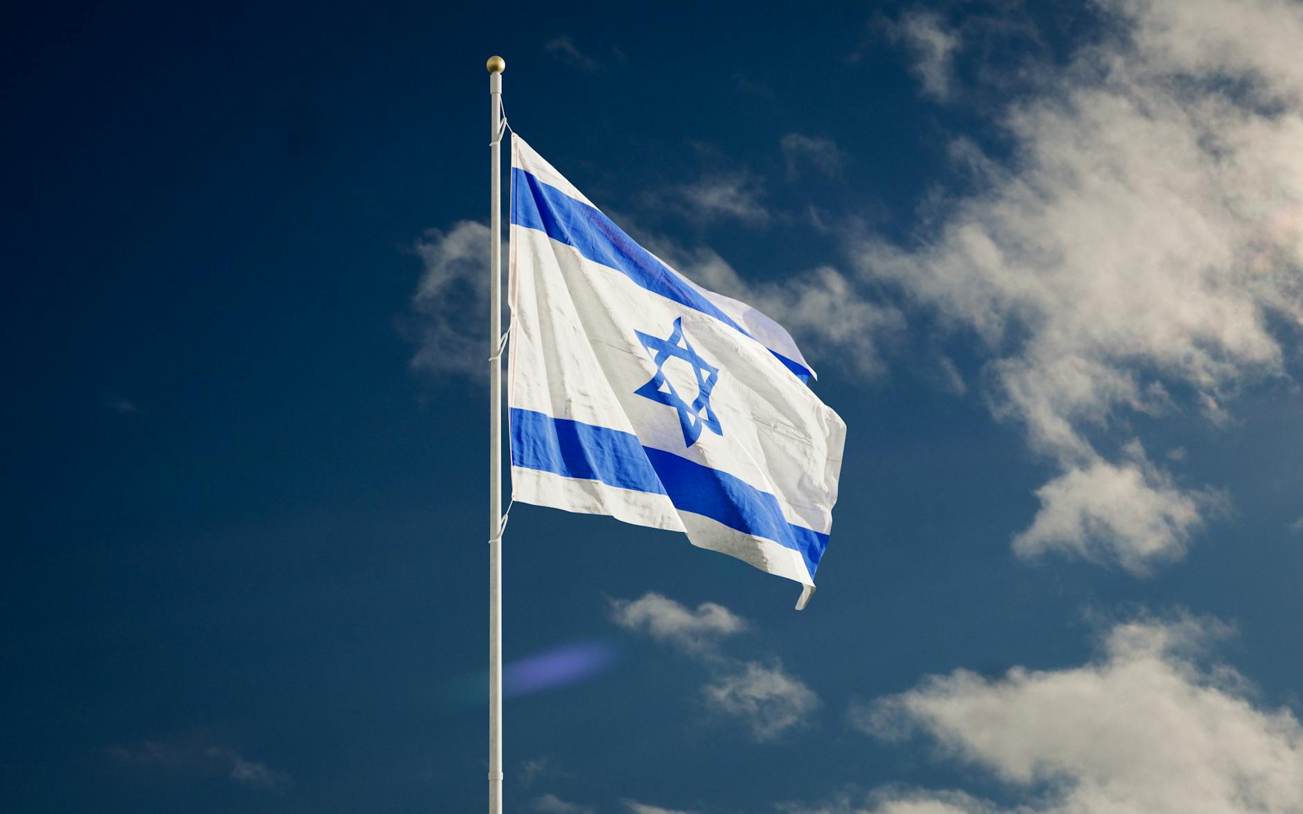 israel flag on a flagpole under the blue sky